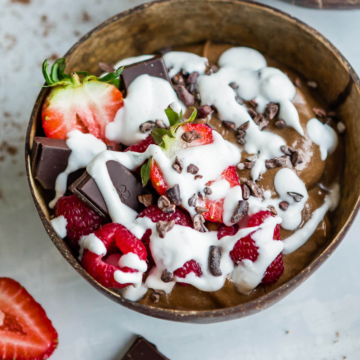 A chocolate smoothie bowls, topped with coconut whipped cream and fresh berries.