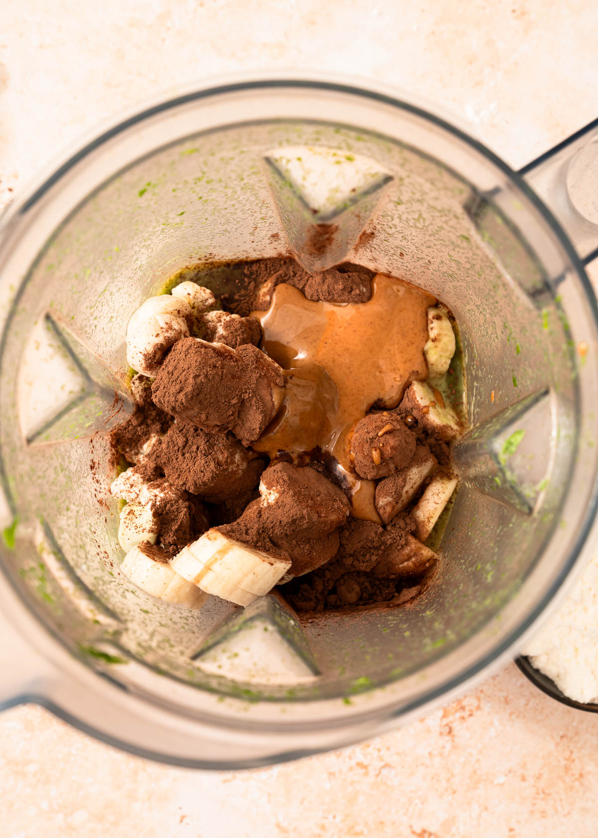 Banana, cocoa powder, and almond butter in a blender container
