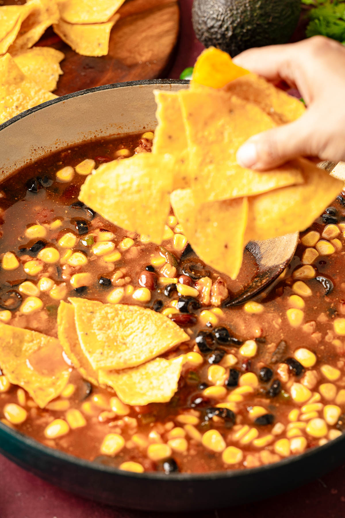 A person adding corn tortilla pieces over the simmered mixture