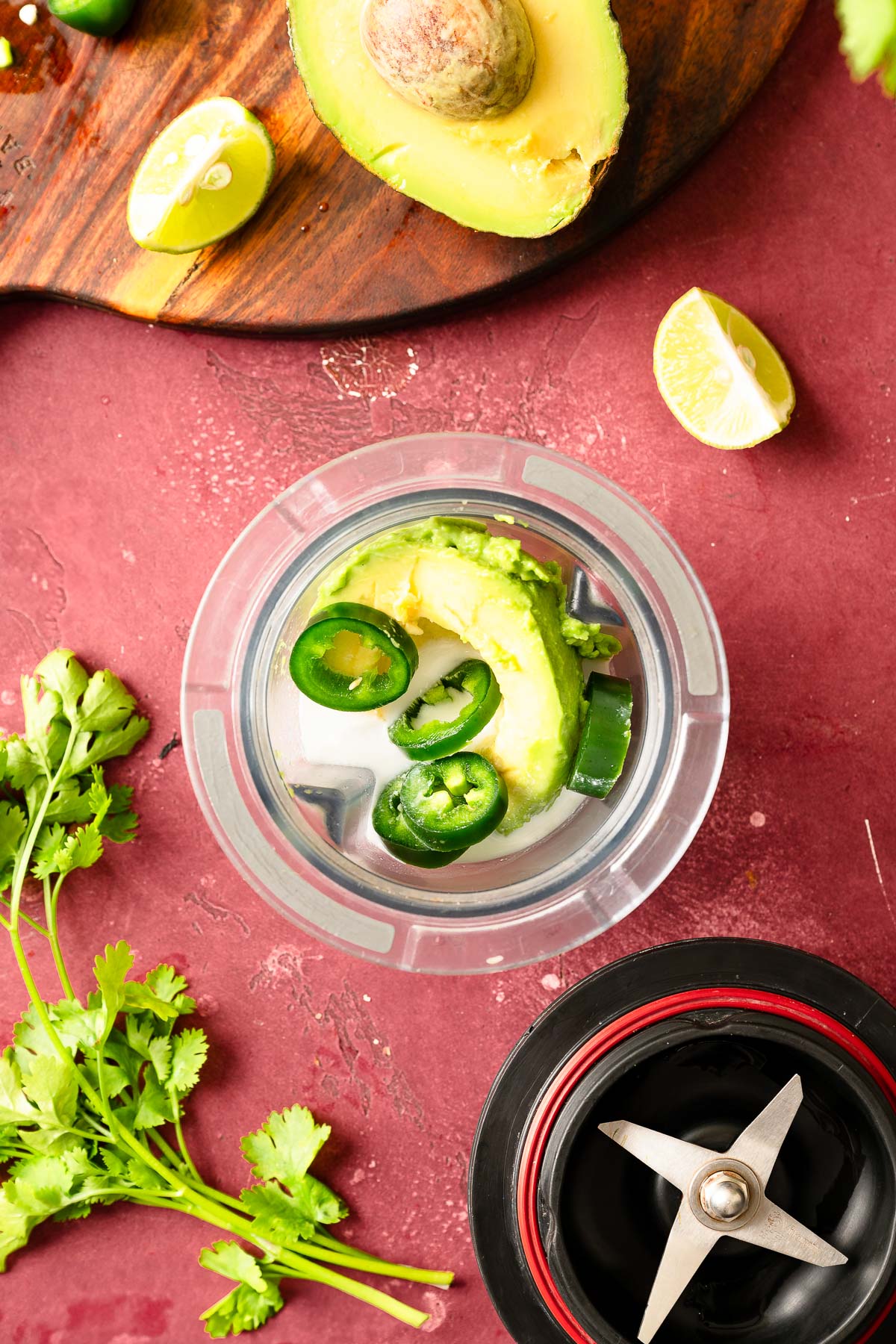 A blender containing sliced avocado and jalapeño