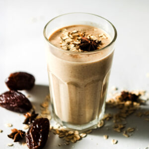 Glass of cinnamon date smoothie with medjool dates and oats on the table.