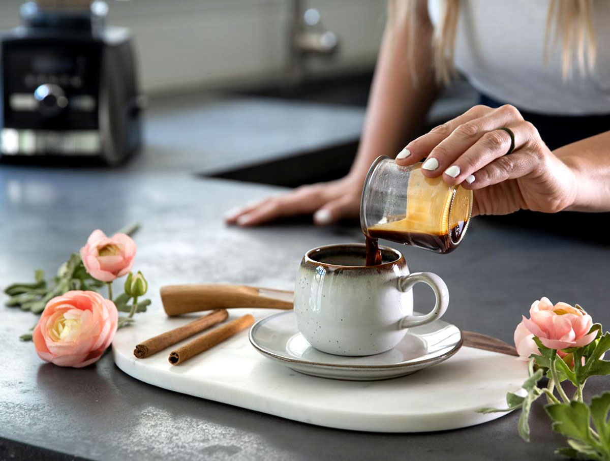 Woman pouring espresso into a mug for a cinnamon dolce latte.