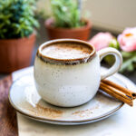 Cinnamon dolce latte in a white mug with cinnamon sticks.