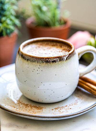 Cinnamon dolce latte in a white mug with cinnamon sticks.