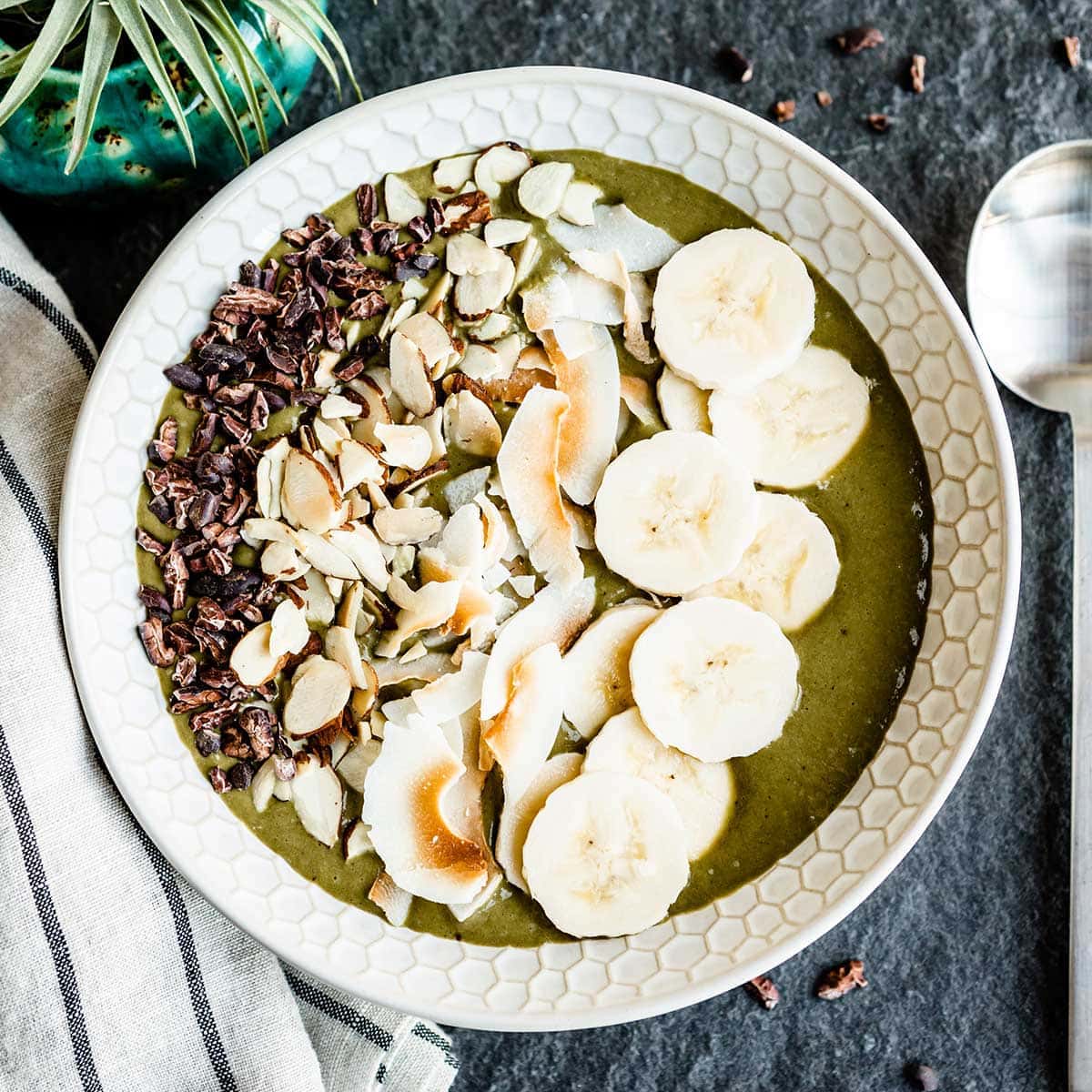 overhead shot of vegan smoothie bowl topped with bananas, toasted coconut and cacao nibs
