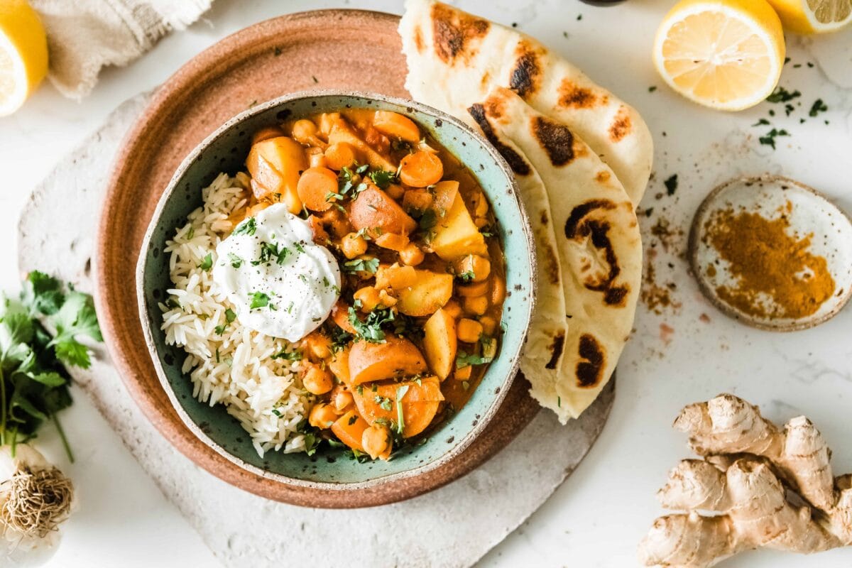Bowl of creamy potato curry with rice and bread.