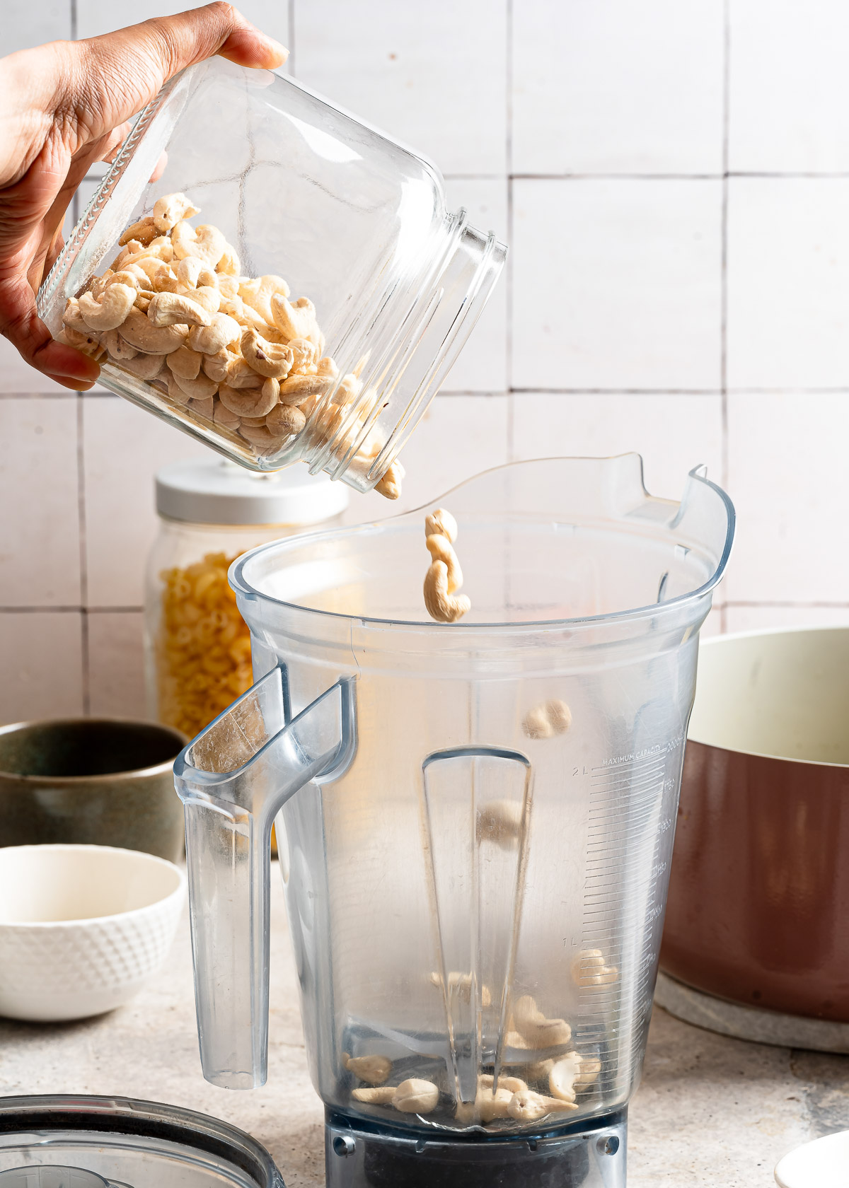 A person adding cashews in a blender