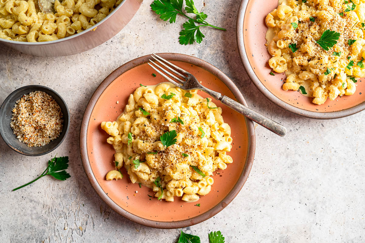 Bowl of vegan mac and cheese topped with breadcrumbs and fresh chopped parsley