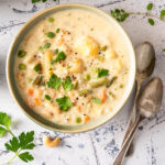 A bowl of ready-to-eat creamy vegetable soup next to silver spoons.