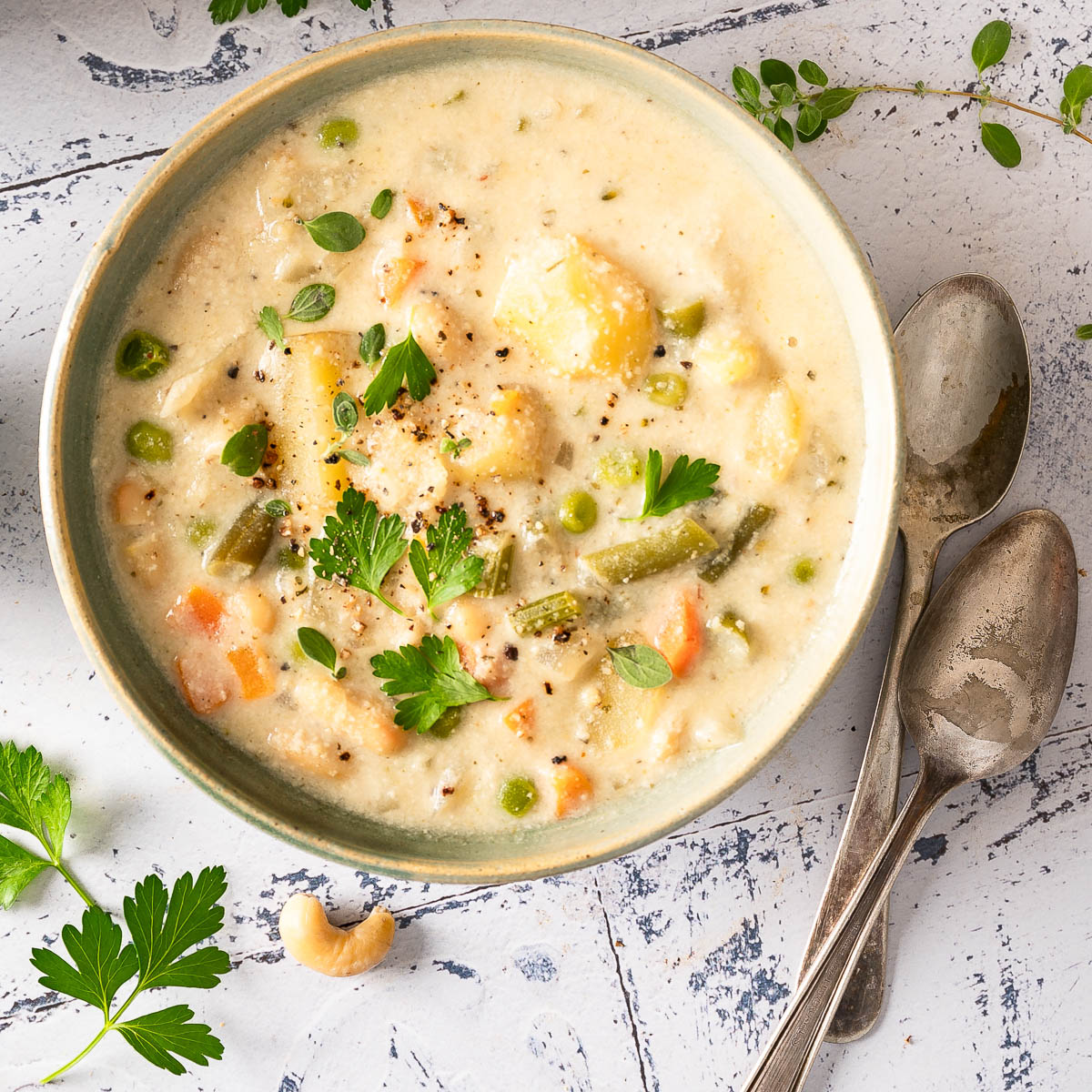 A bowl of ready-to-eat creamy vegetable soup next to silver spoons.