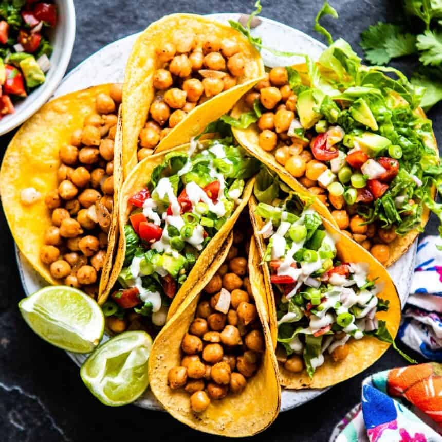 A plate full of chickpea tacos with fresh toppings.