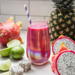 Pink tropical smoothie surrounded by fresh ingredients