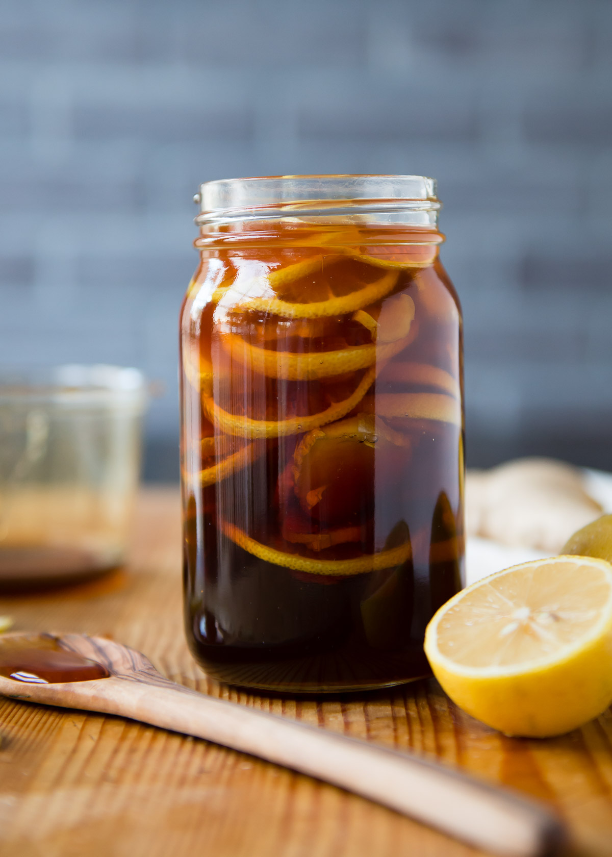 Open jar of homemade Ginger Lemon Honey Tea next to a wooden spoon.