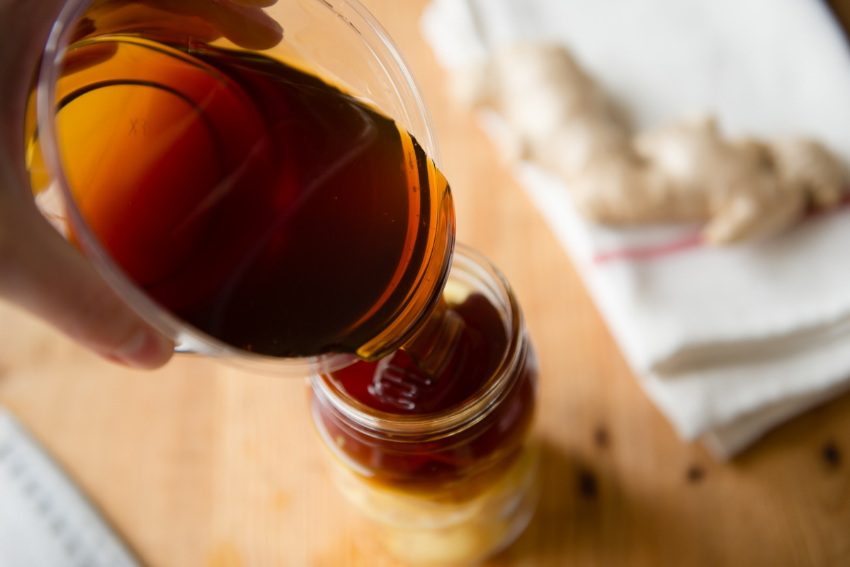 Pouring raw honey into Ginger Lemon Honey Tea jar.