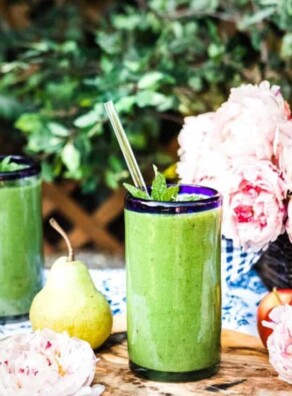 2 glasses of green smoothie recipe for glowing skin topped with fresh mint and a glass straw.