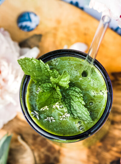 Glowing green smoothie in a glass with mint leaves on top