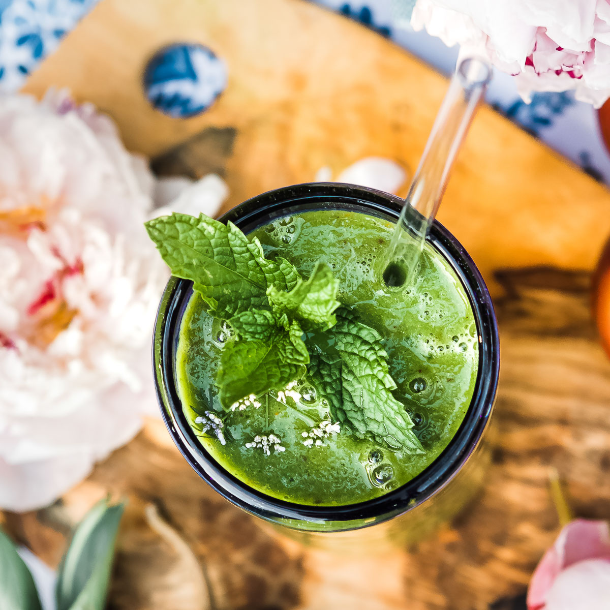 Glowing green smoothie in a glass with mint leaves on top