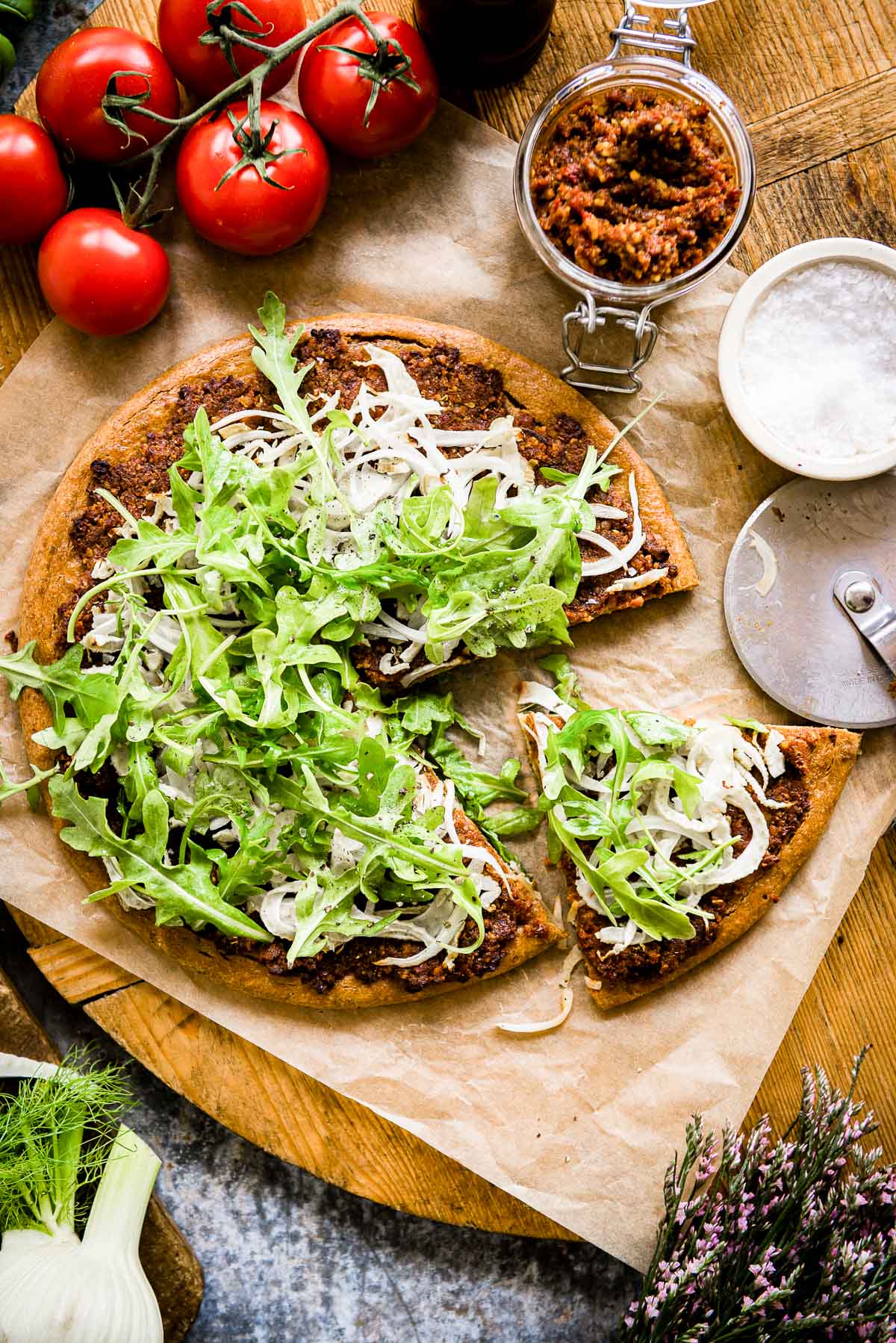 loaded pizza using a gluten-free crust and topped with sun-dried tomato pesto, arugula and fennel.