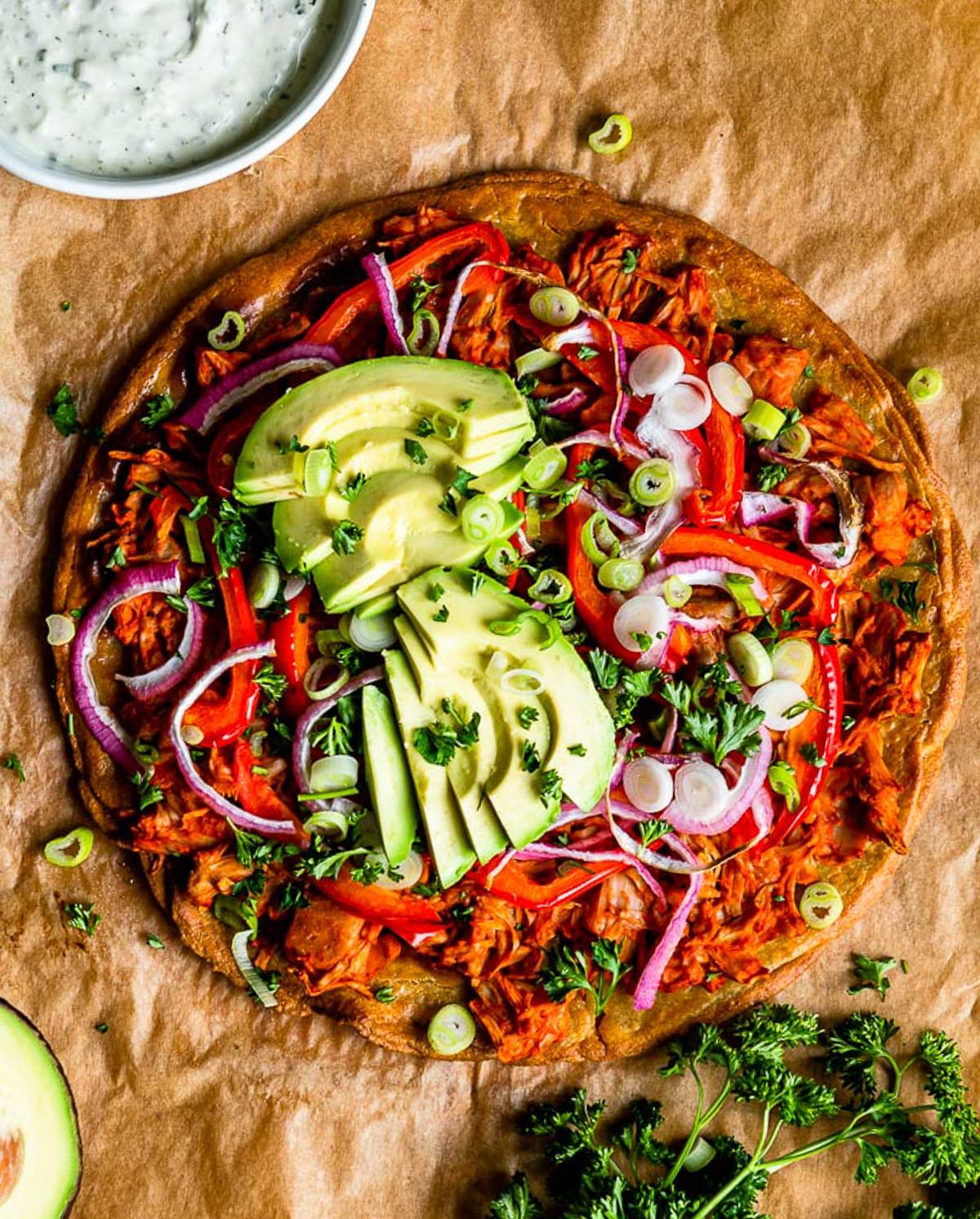 buffalo jackfruit pizza using a gluten-free pizza crust on parchment paper.