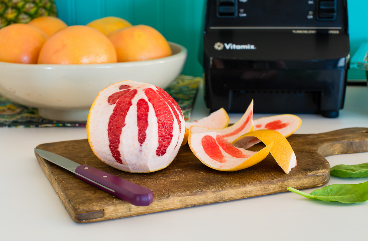 A peeled grapefruit on a wooden cutting board