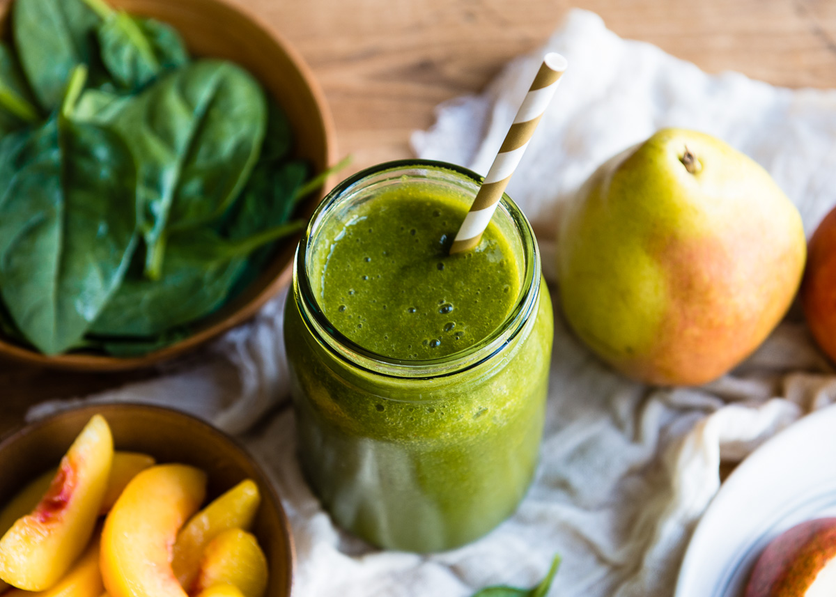 A glass of pear smoothie surrounded by ingredients