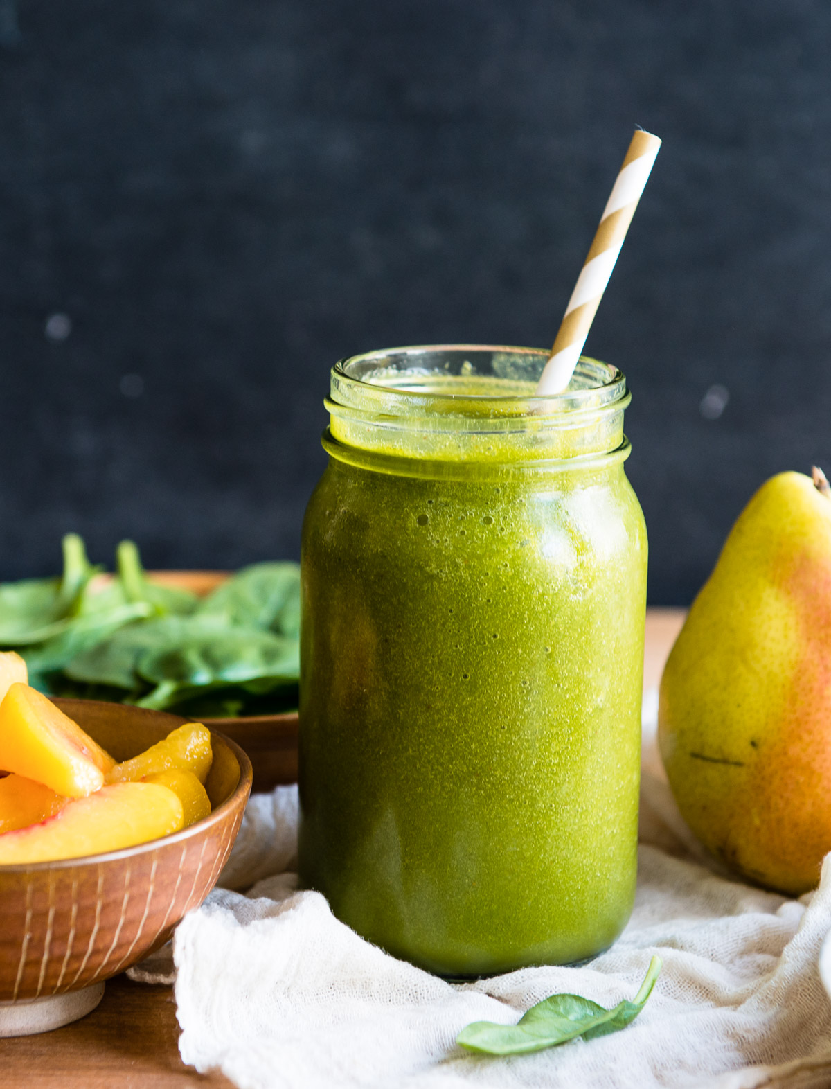 Pear smoothie served in a mason jar glass with a striped straw