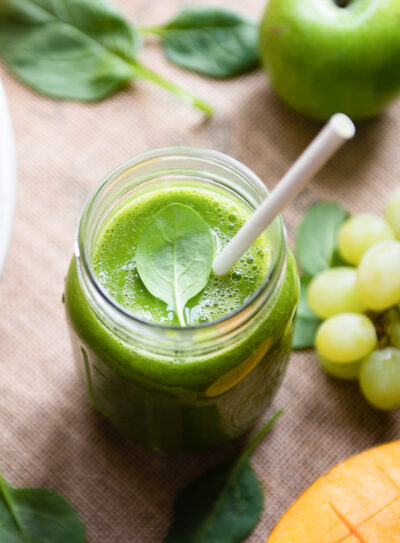 A glass of fresh green tea smoothie with a straw