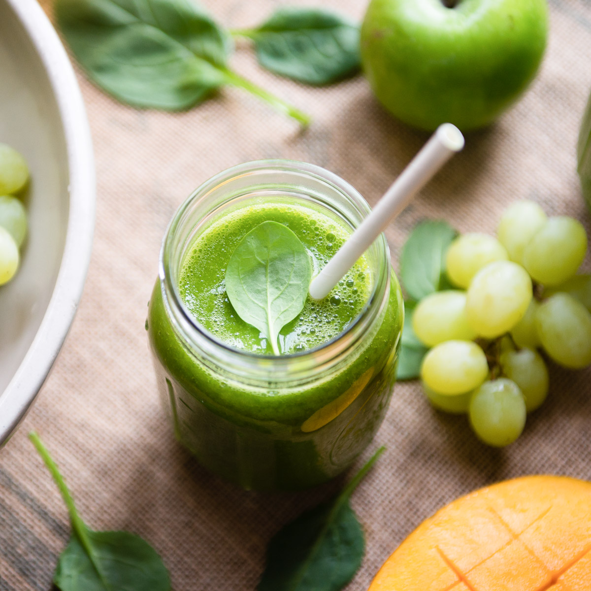 A glass of fresh green tea smoothie with a straw