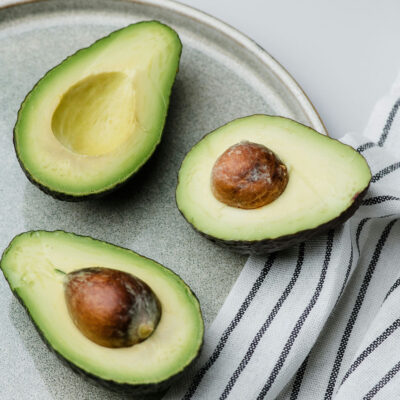 Three halves of avocados arranged attractively on a modern gray plate.