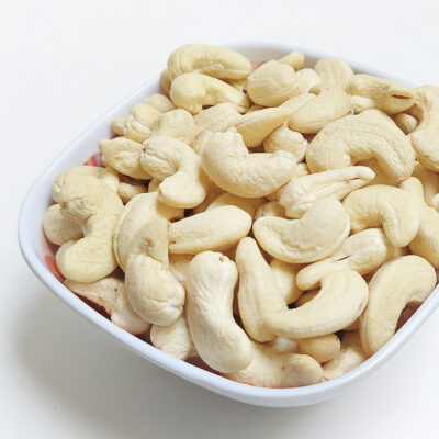 Close-up of a bowl filled with cashews on a white countertop.