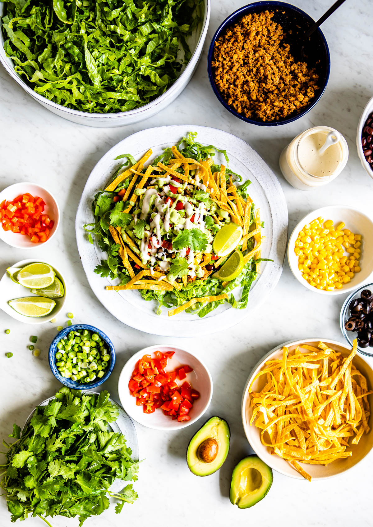 Delicious healthy taco salad recipe on a plate, with fresh toppings arranged around it.