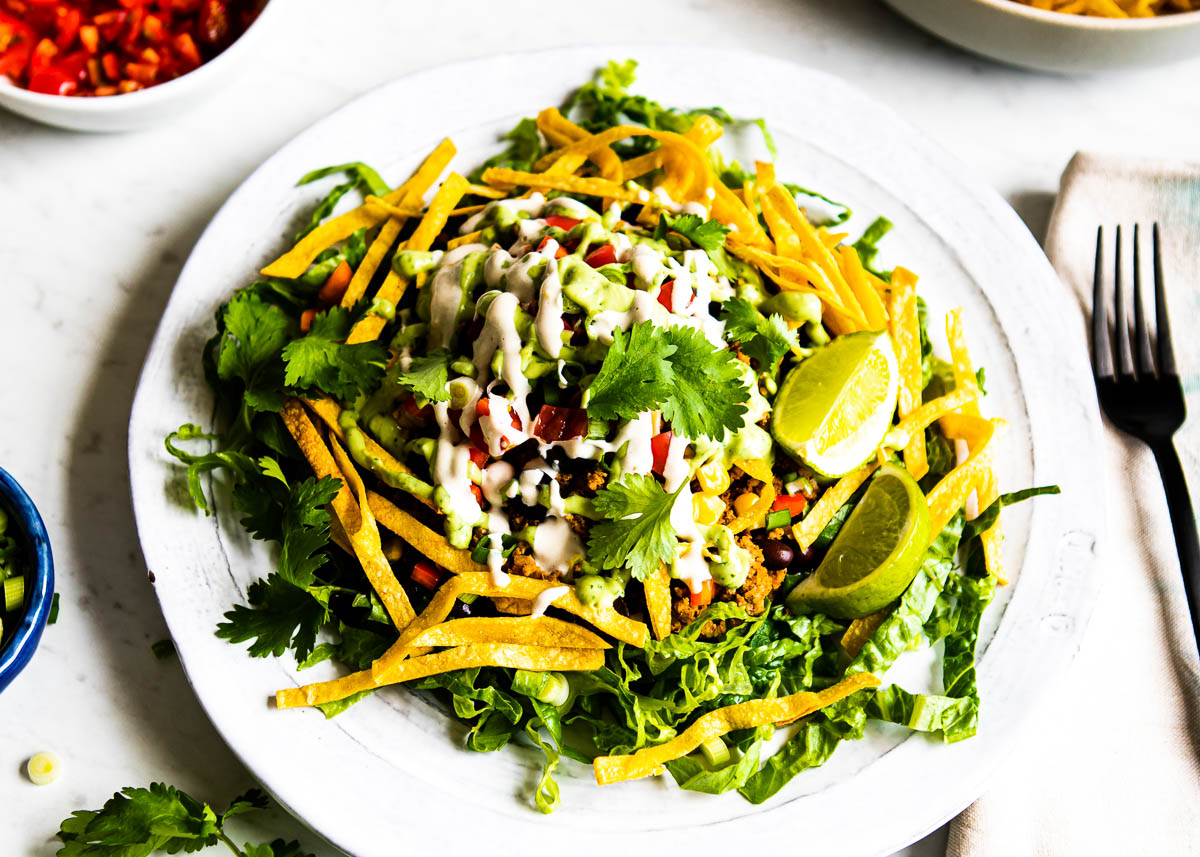 Easy and healthy taco salad recipe served on a plate, garnished with fresh toppings.