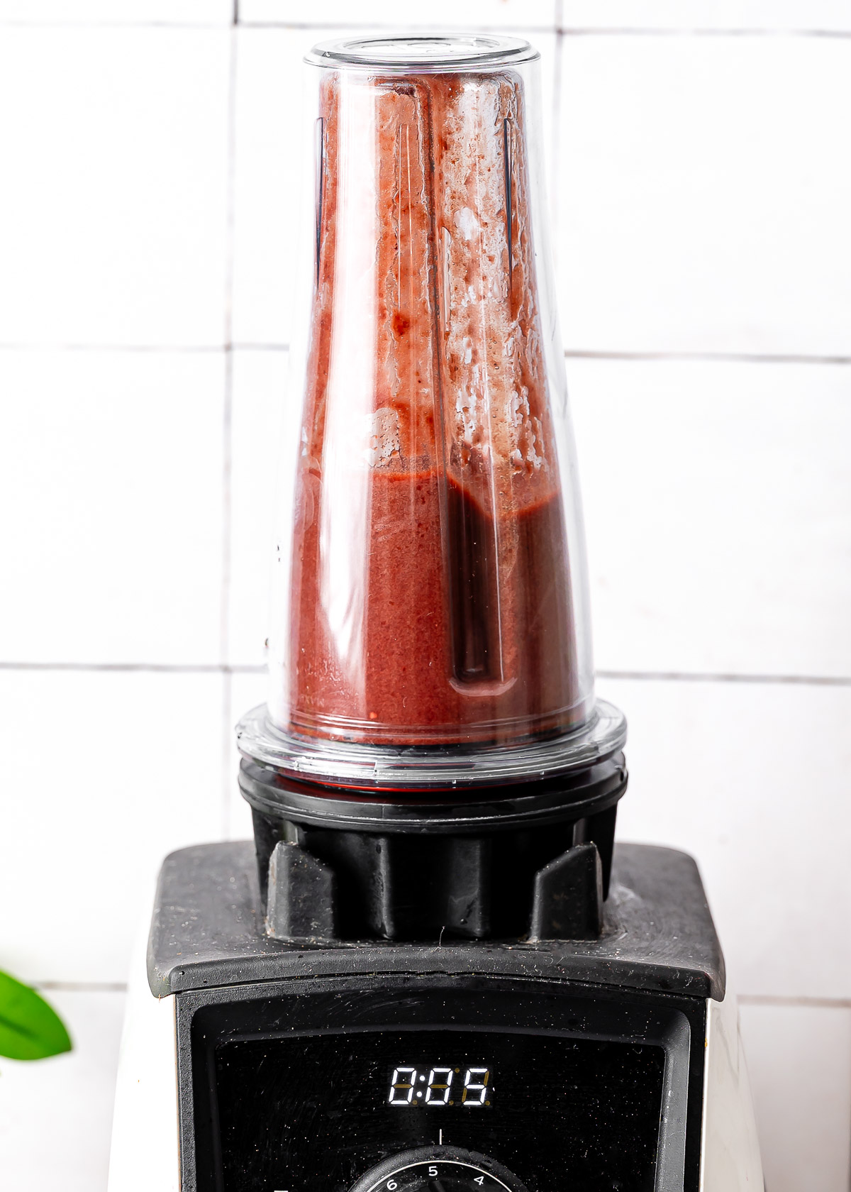 A blender with a red cherry limeade mixture spinning inside.