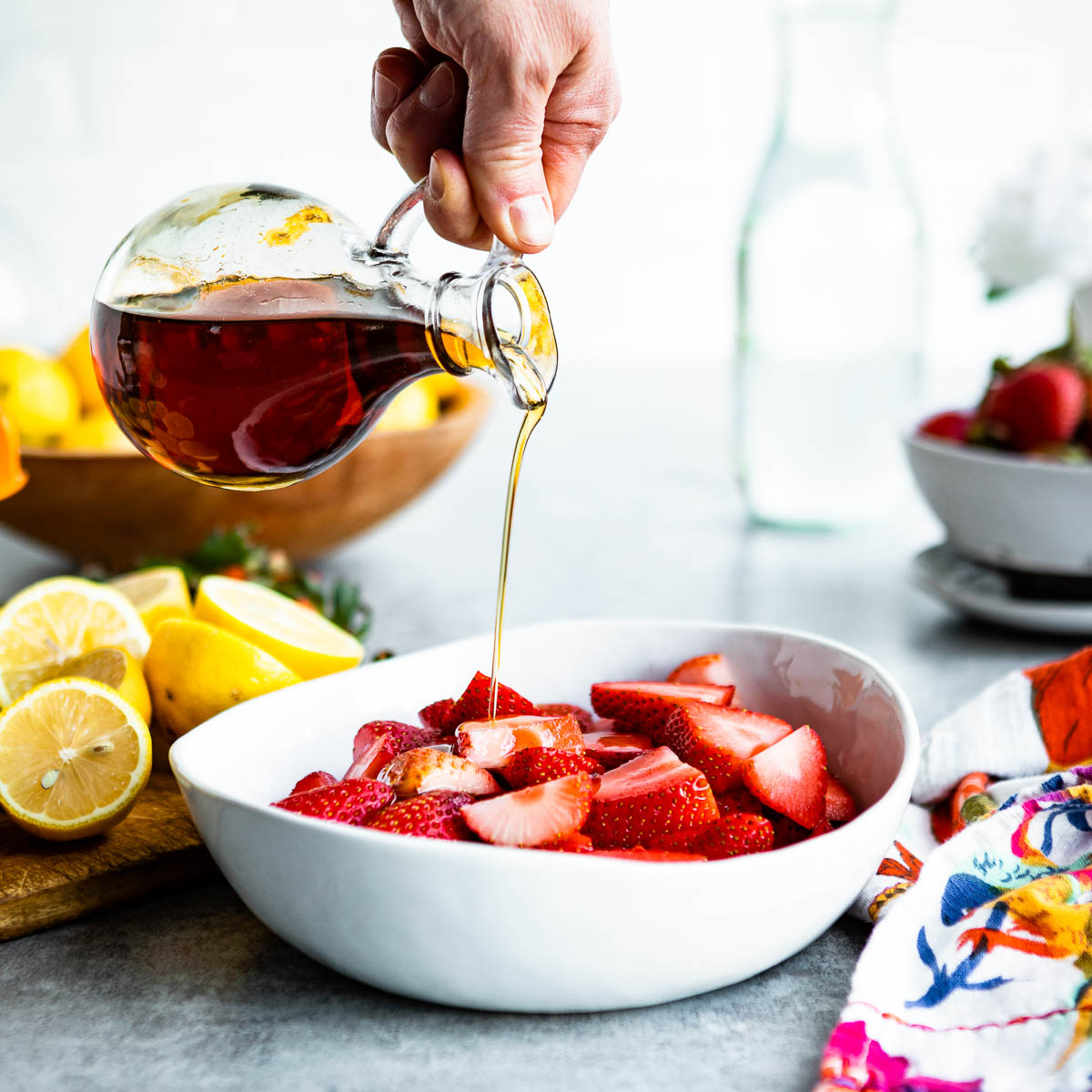 pouring maple syrup over sliced strawberries
