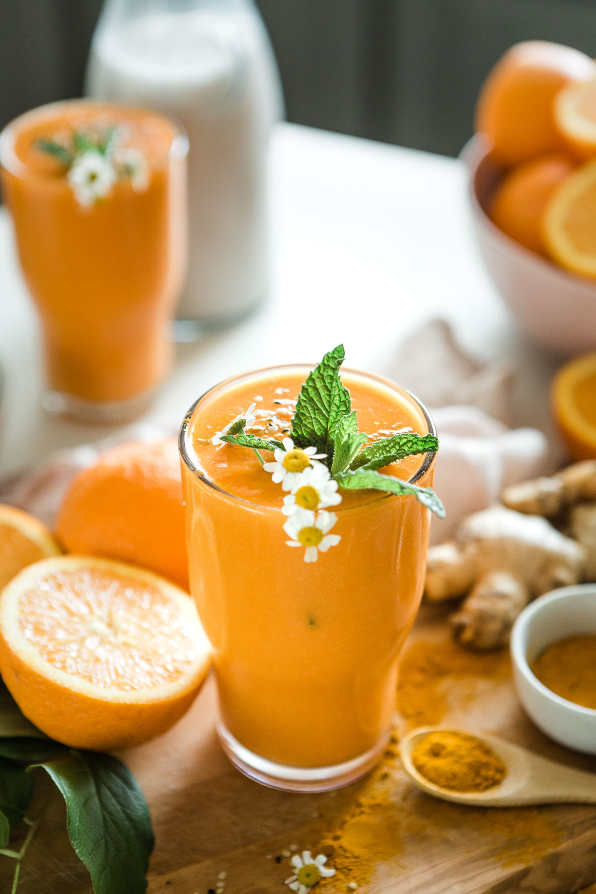 A glass of turmeric smoothie surrounded by ingredients
