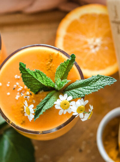 A glass of turmeric smoothie with a floral-inspired topping