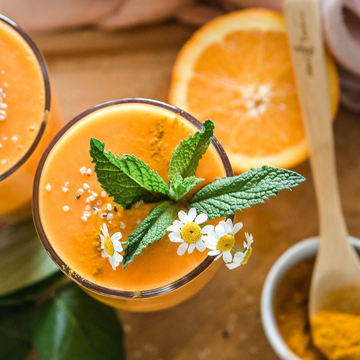 A glass of turmeric smoothie with a floral-inspired topping