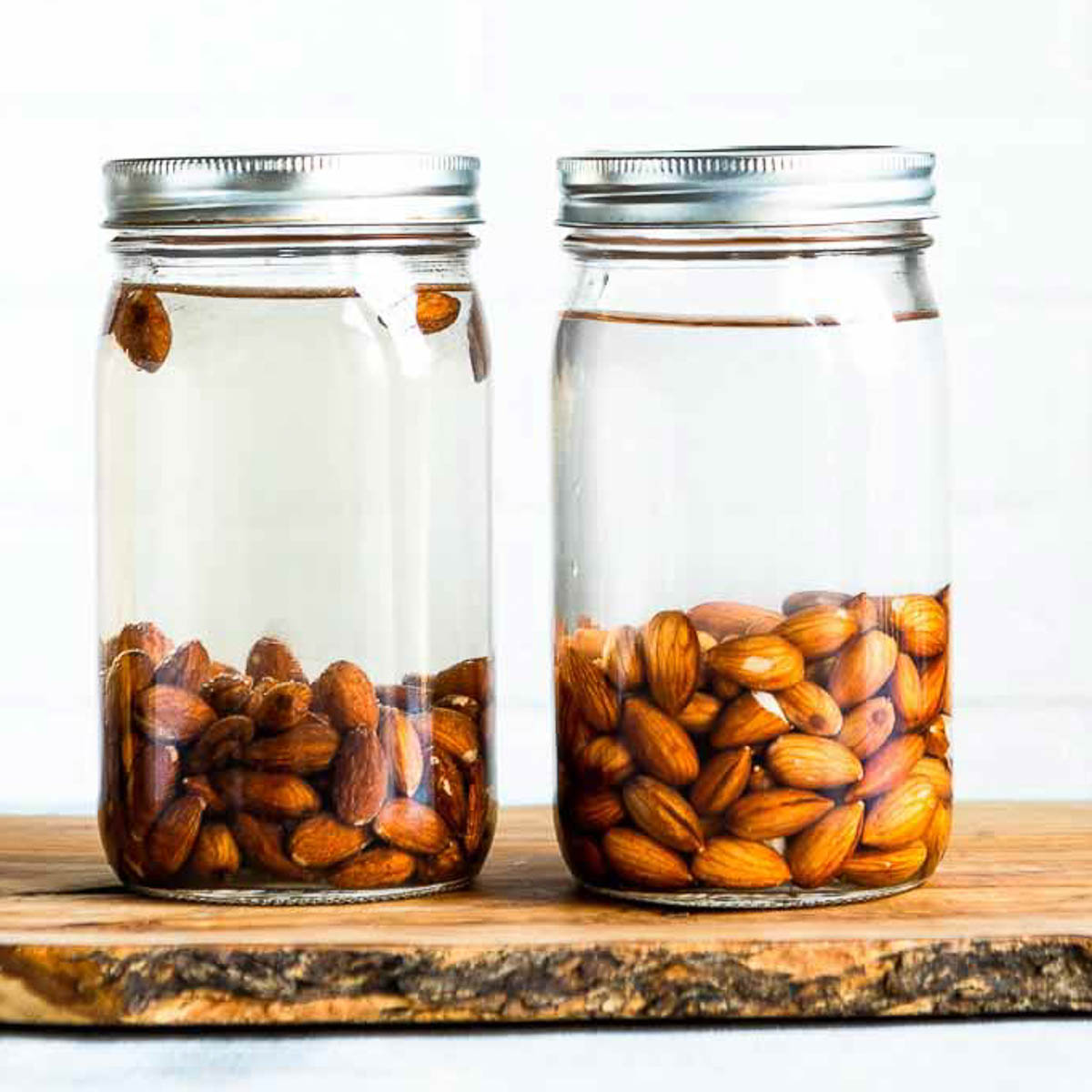 Two jars of almonds soaking in water.