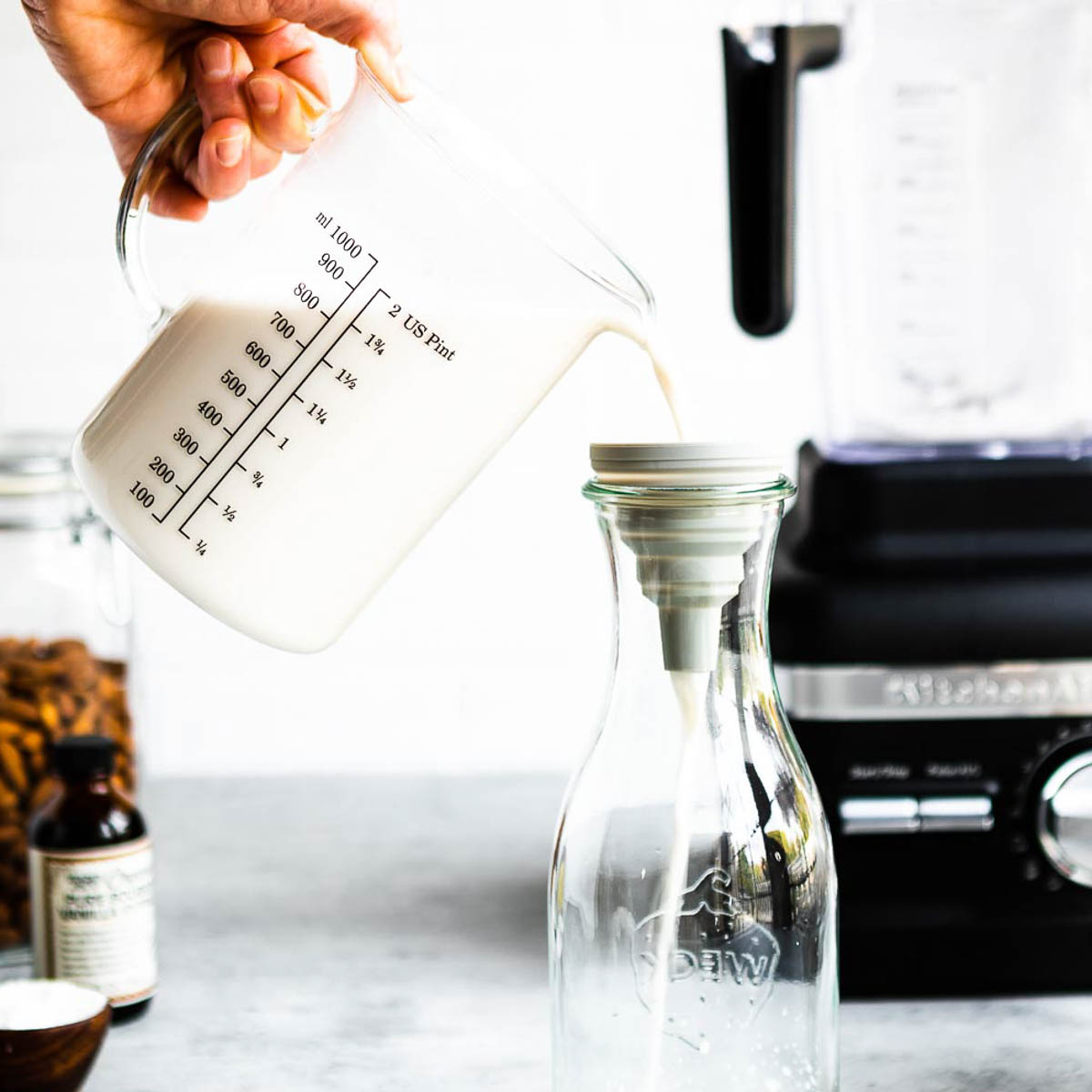 pouring the measuring cup through a funnel into a glass jar