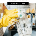 Yellow gloves washing a blender container.