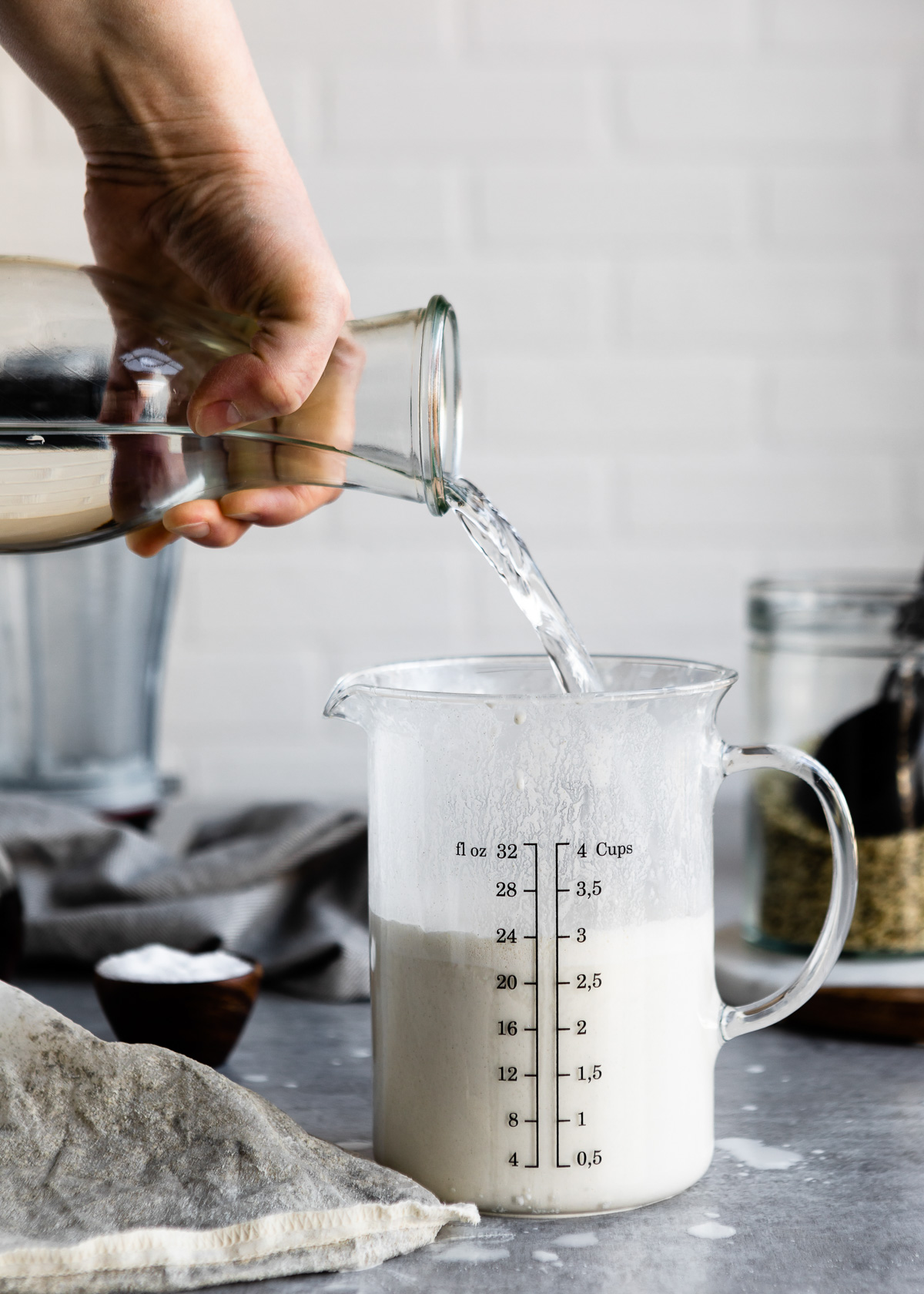 Adding water to a measuring cup of homemade hemp milk.