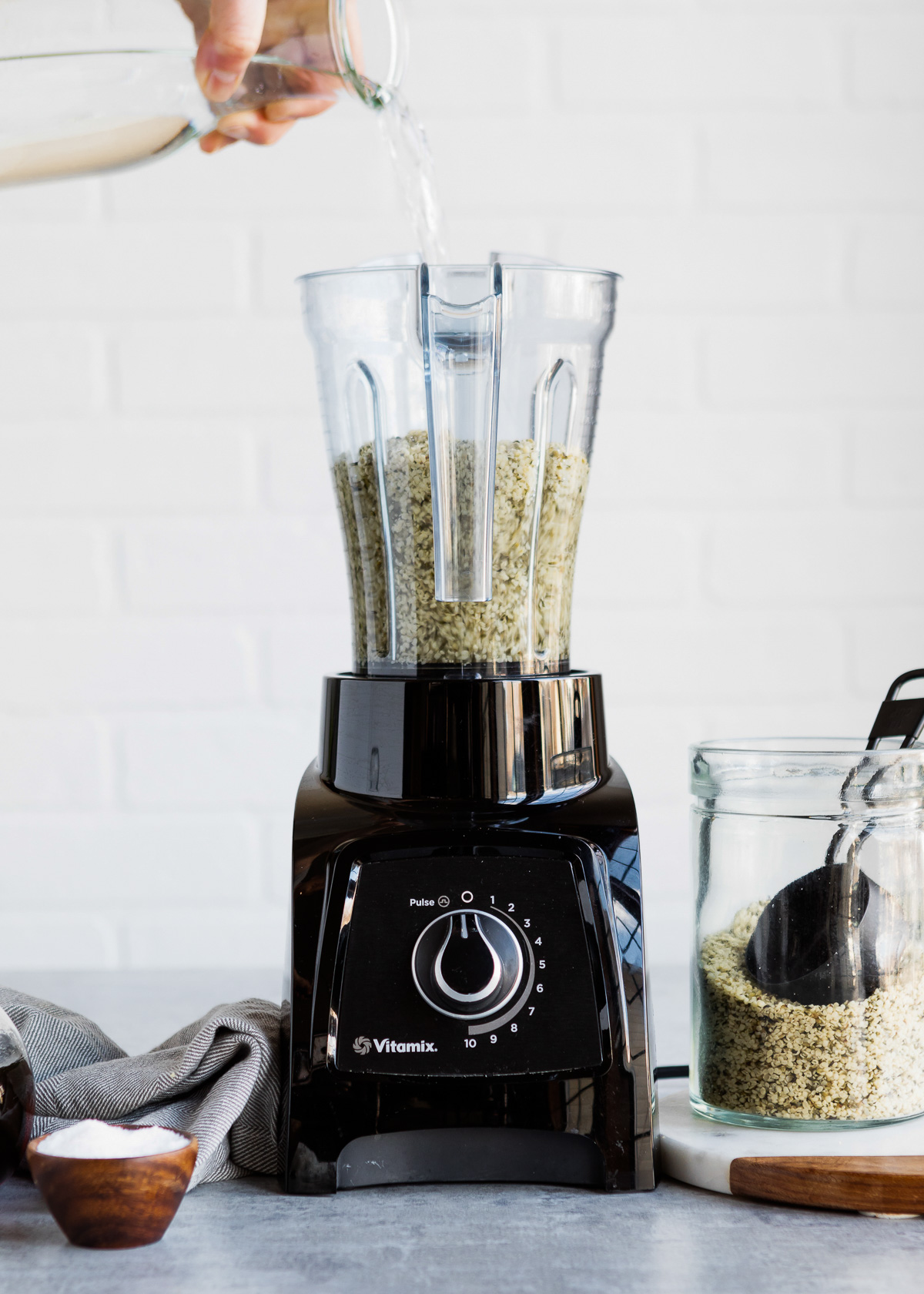 Pouring water into blender with hemp seeds.