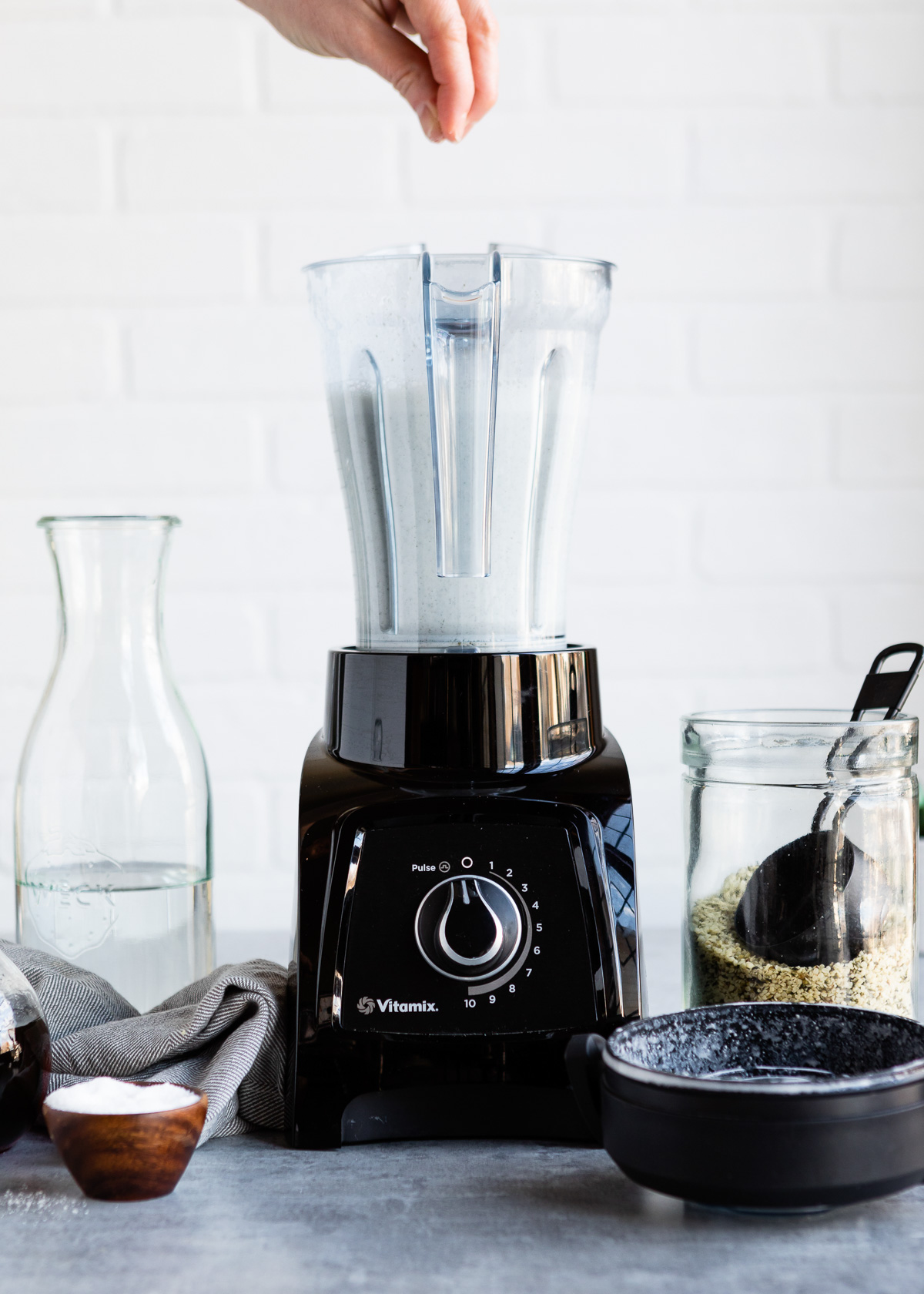 Sprinkling sea salt into blender container with hemp seeds and water.