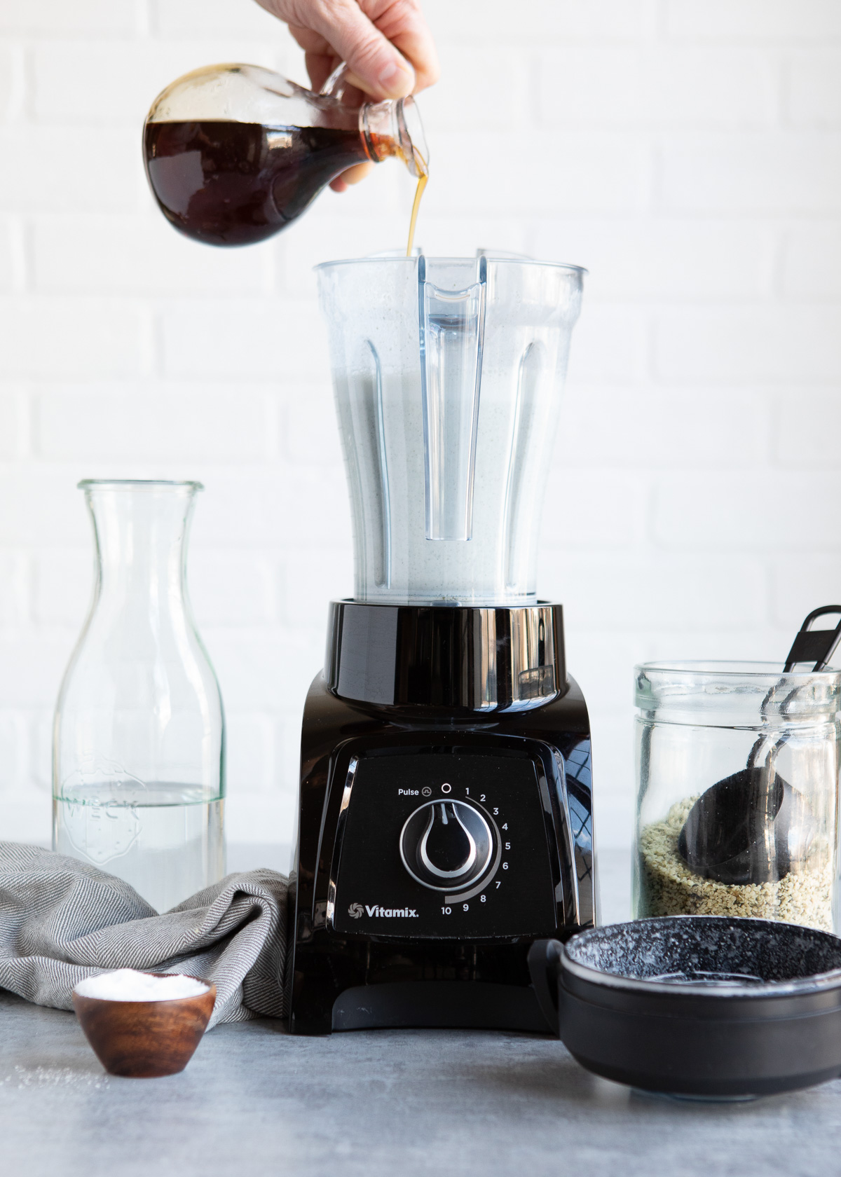 Pouring maple syrup into blender with hemp milk.