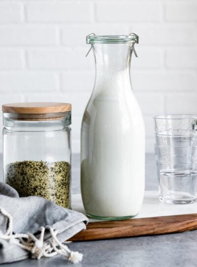 Homemade hemp milk next to a jar of hemp hearts.