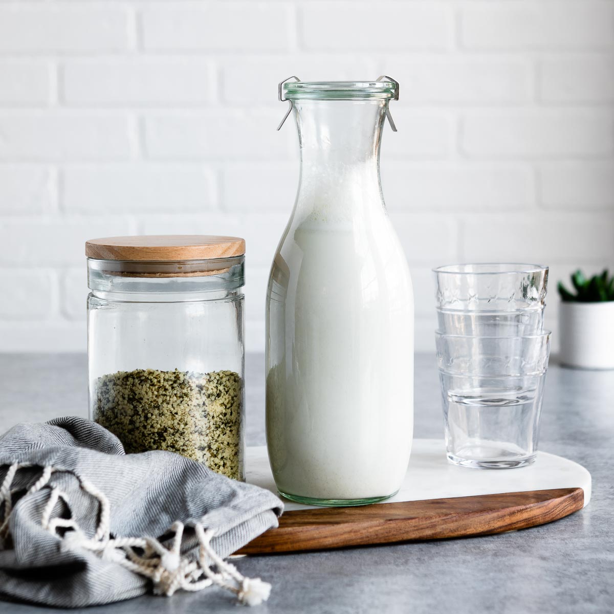 Homemade hemp milk next to a jar of hemp hearts.