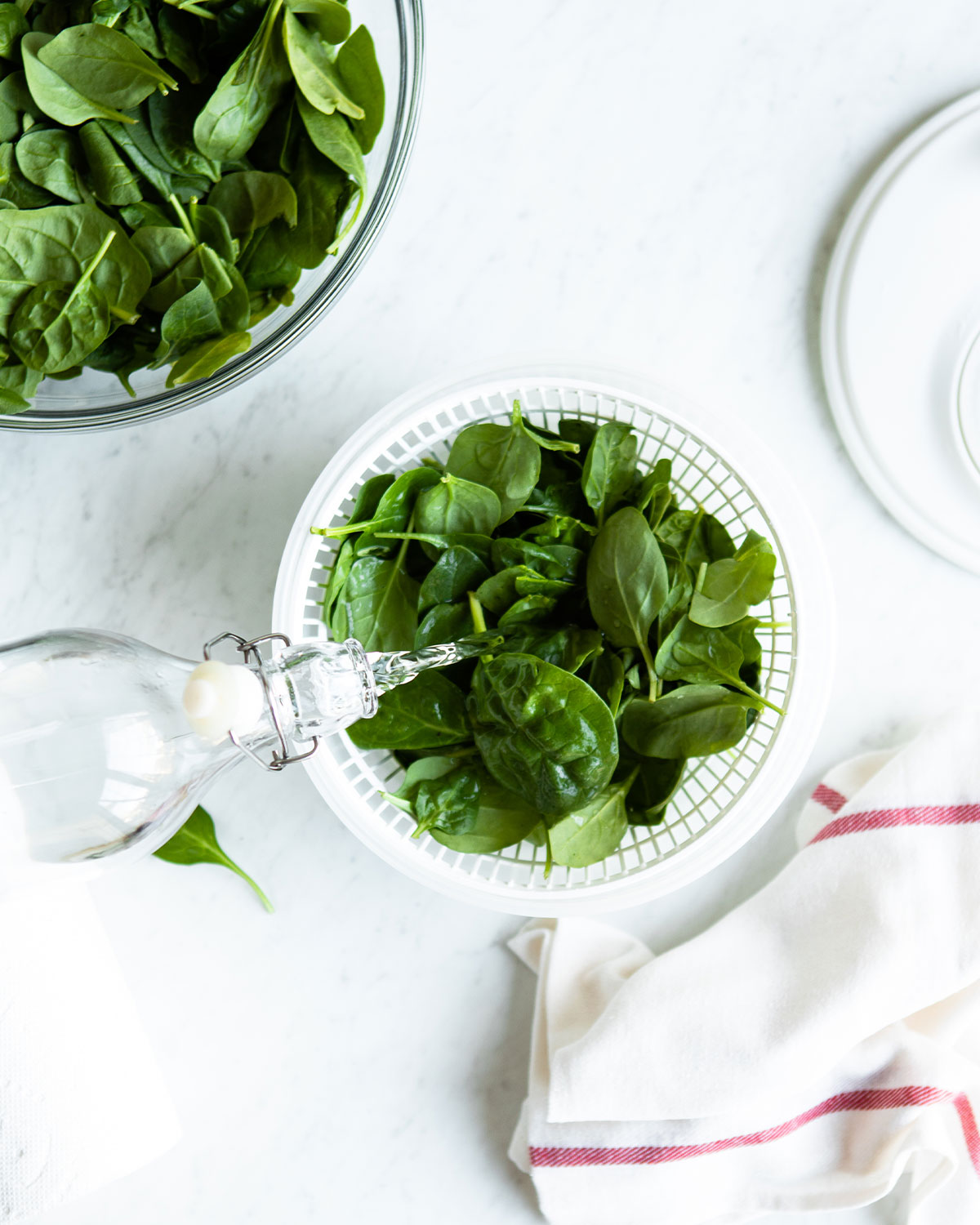 Pouring water over a bowl of spinach to wash it. 