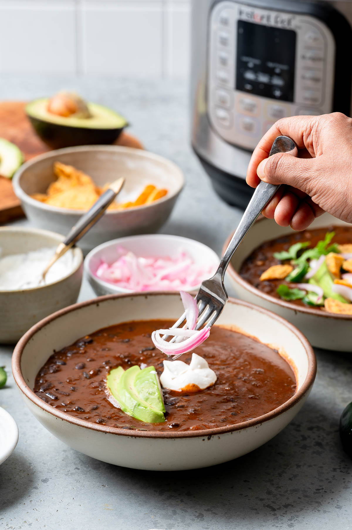 Person using a fork to stir hearty instant pot black bean soup in a bowl