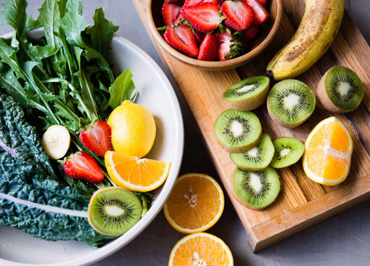 Fresh fruits and greens arranged on a countertop, ready for making a kiwi citrus smoothie.