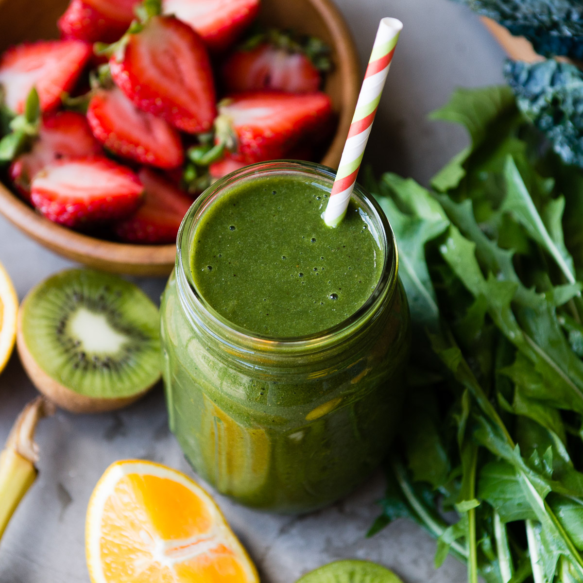 Citrus kiwi smoothie in a jar with fruits and greens.
